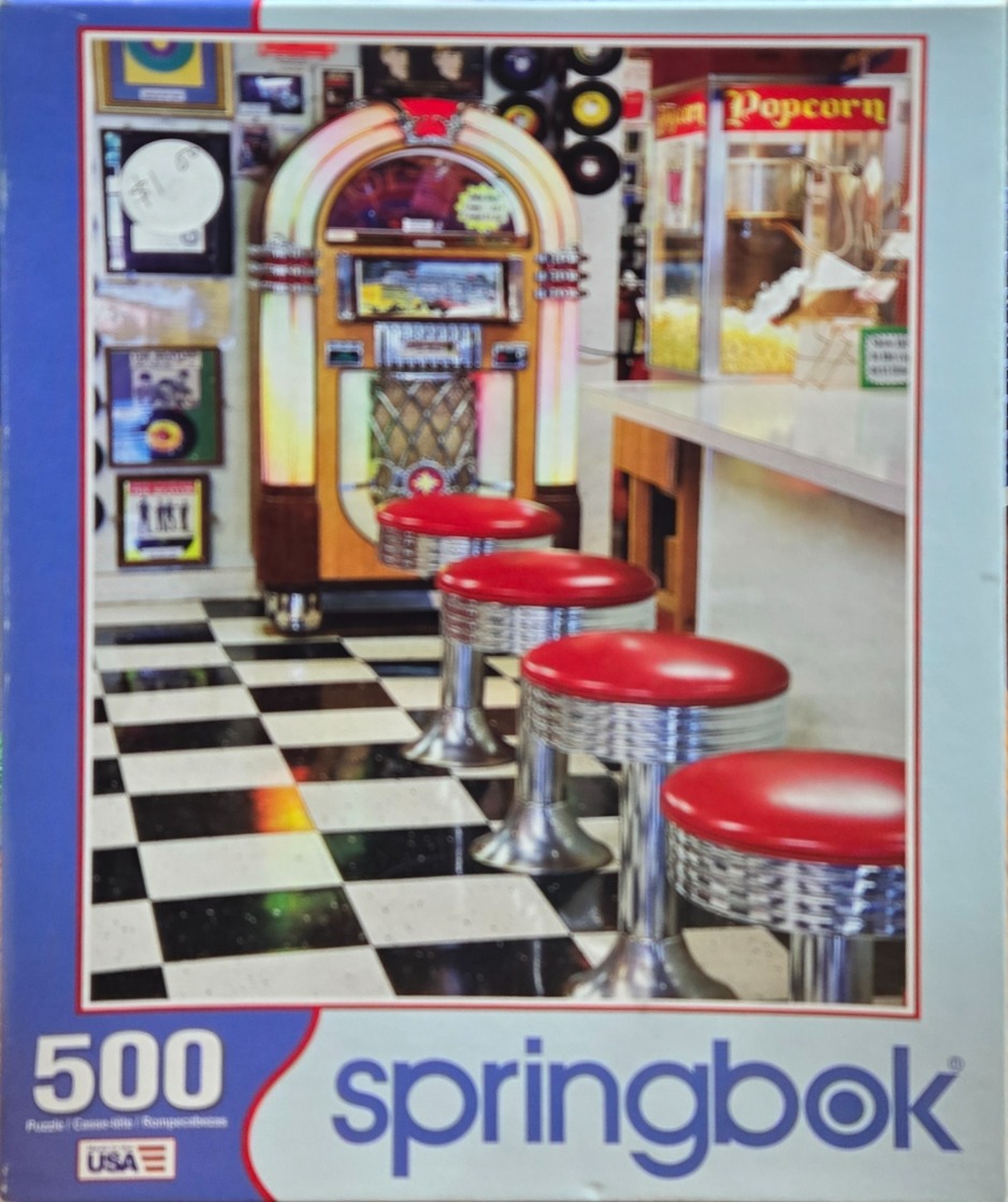 Interior view of a 1950s-style retro diner with a jukebox and chrome stools on a checkerboard floor.
