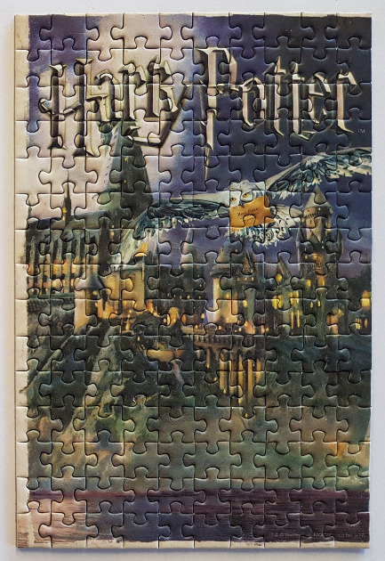 A fantasy illustration of Hogwarts castle at twilight with a snowy owl flying overhead and the Harry Potter logo.