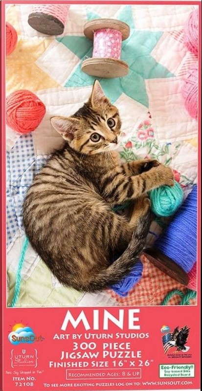 A tabby kitten playing with colorful balls of yarn on a patchwork quilt.