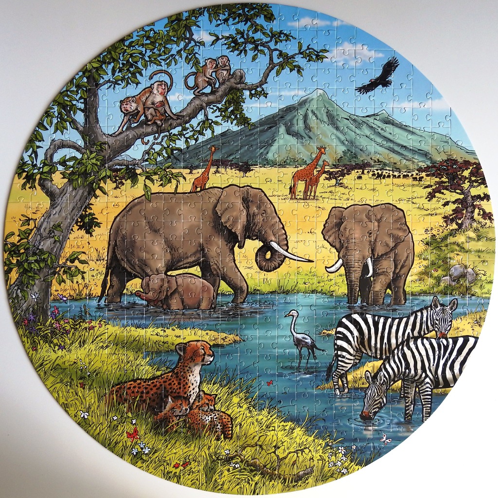 A circular illustration of a vibrant African savanna landscape filled with various wild animals around a watering hole.