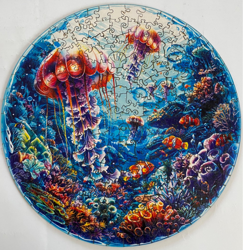 Round illustration of a vibrant coral reef scene with large, glowing jellyfish and clownfish.