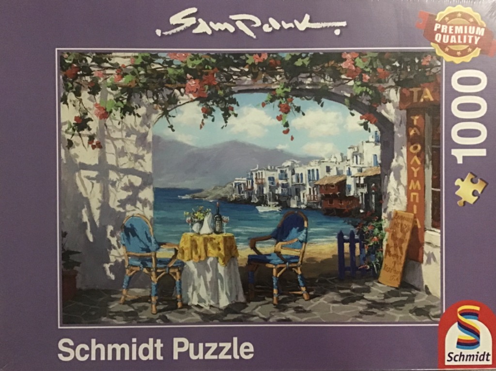 A Mediterranean terrace scene with a table set for two overlooking a coastal village and sea.