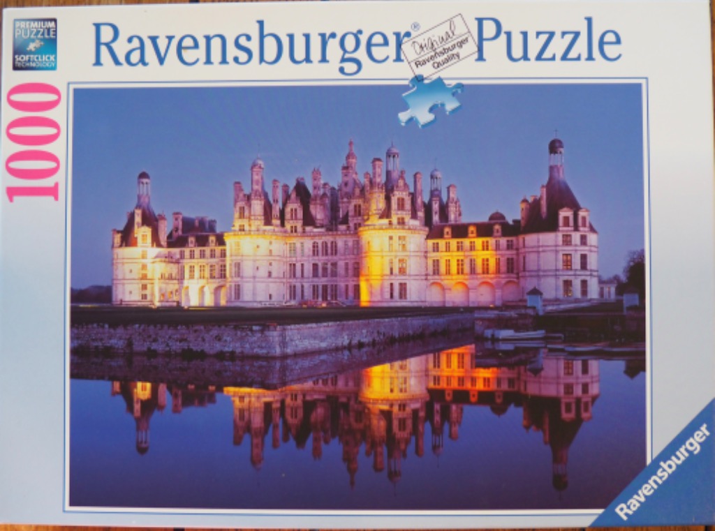 The French Chateau de Chambord illuminated at twilight, reflected in still water.