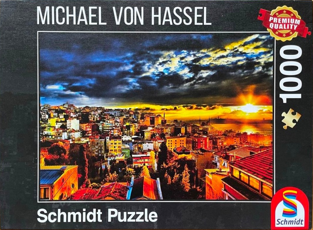 A vibrant sunset over a densely populated coastal city with deep blue clouds and bright orange light.