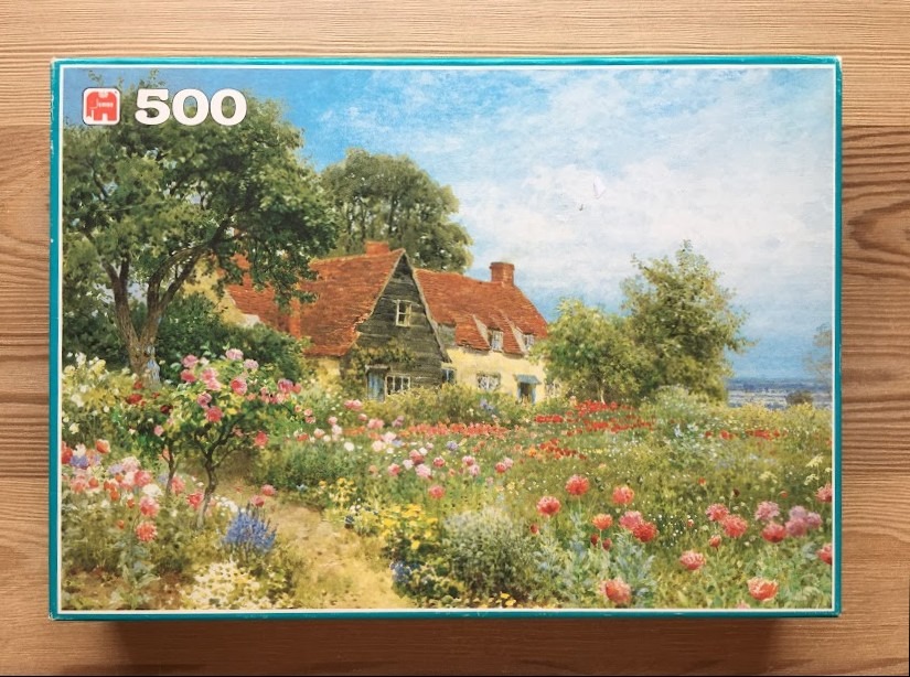 Painting of an English cottage with a vibrant wildflower garden in summer.