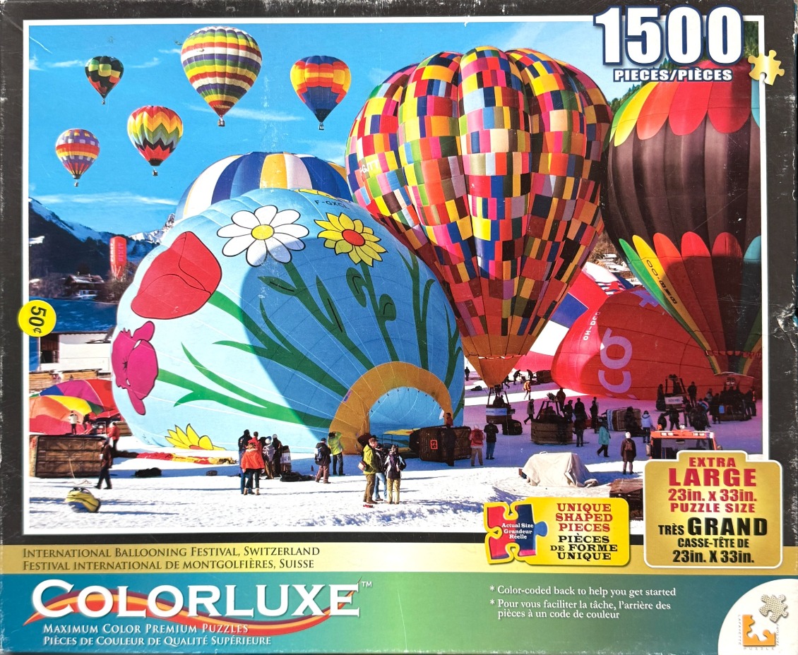 Many colorful hot air balloons on a snowy field with mountains in the background