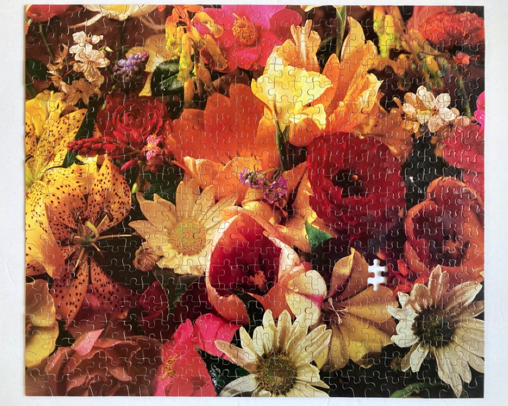 A lush, densely packed bouquet of autumn-toned flowers in shades of red, orange, yellow, and cream.