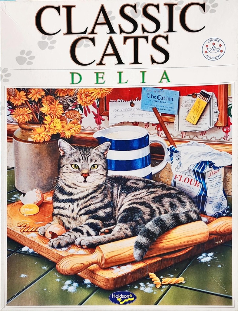 A tabby cat lying on a wooden baking board in a kitchen setting with flour, eggs, and a jug of milk.