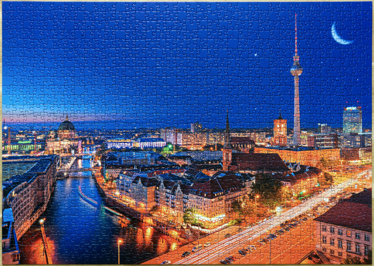 Panoramic view of Berlin at dusk with the TV Tower and a crescent moon in the sky.
