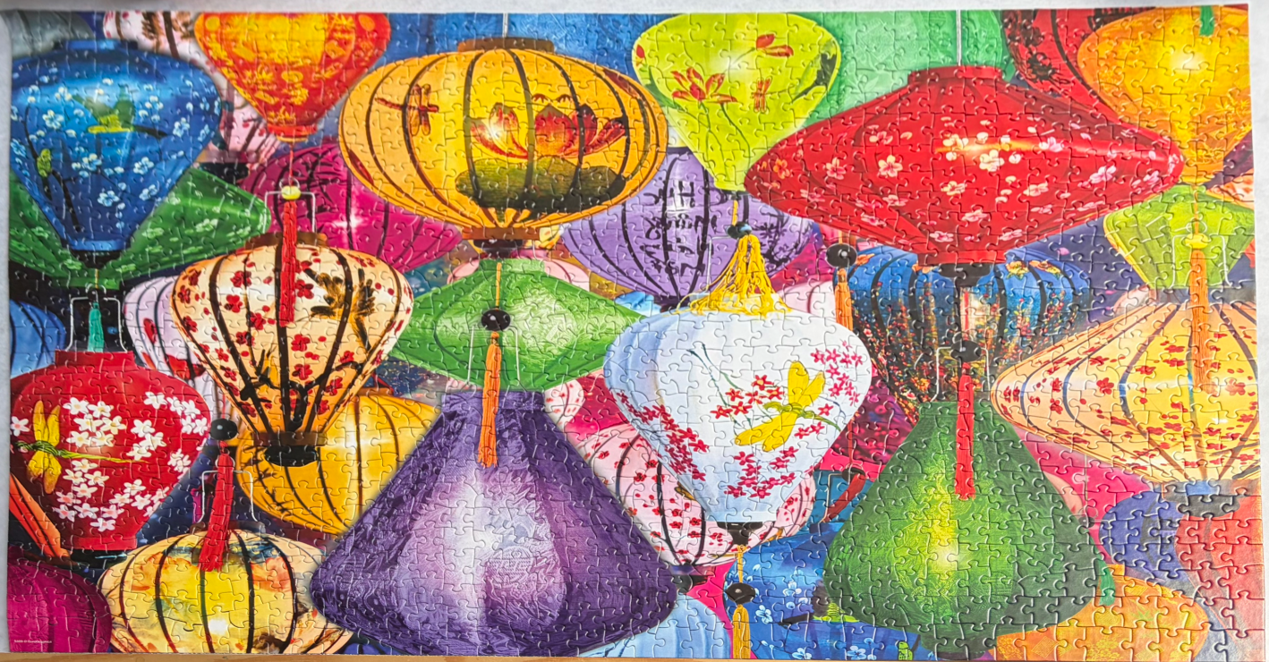 A vibrant, overlapping display of colorful traditional Asian paper lanterns with floral and dragonfly motifs.