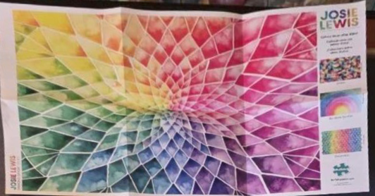 An abstract watercolor image featuring a rainbow-colored radial geometric pattern of interlocking diamonds.
