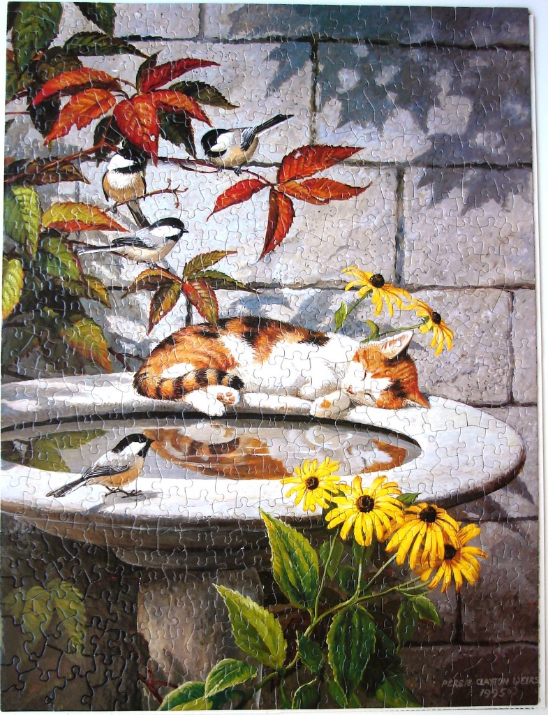 A calico cat sleeping on a stone birdbath surrounded by black-capped chickadees and yellow flowers.
