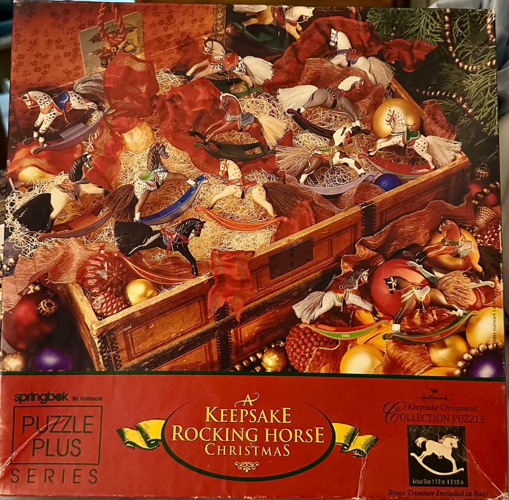 A collection of miniature rocking horse ornaments nestled in straw inside a wooden chest.