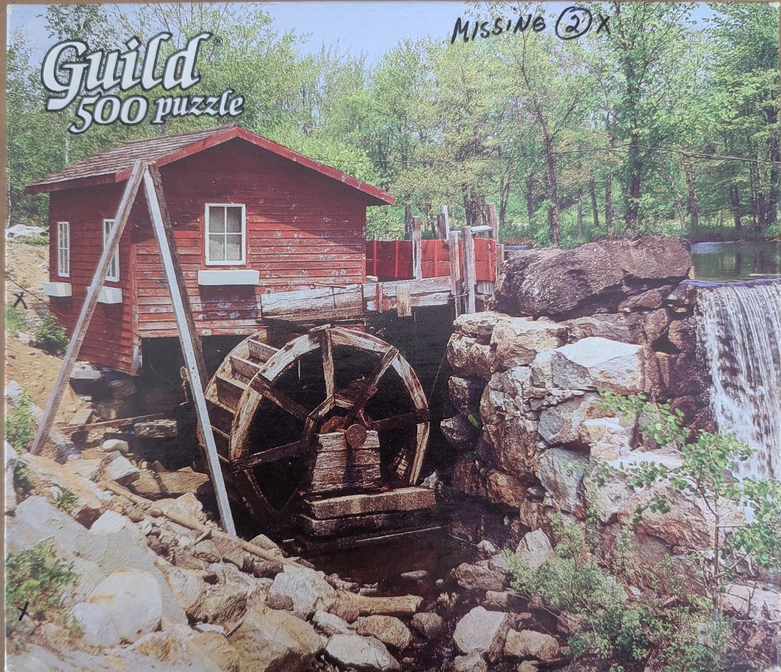A rustic red wooden water mill situated beside a rocky waterfall in a forest setting.