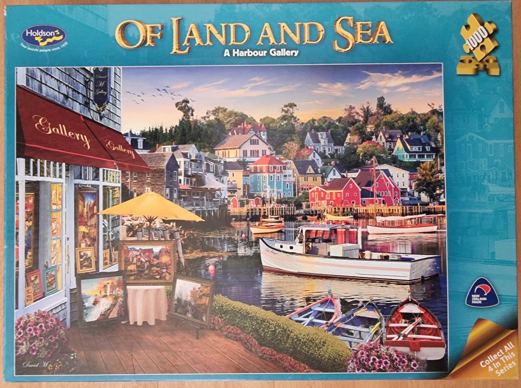 A peaceful harbour scene with an art gallery on a wooden deck overlooking boats and colourful coastal buildings.