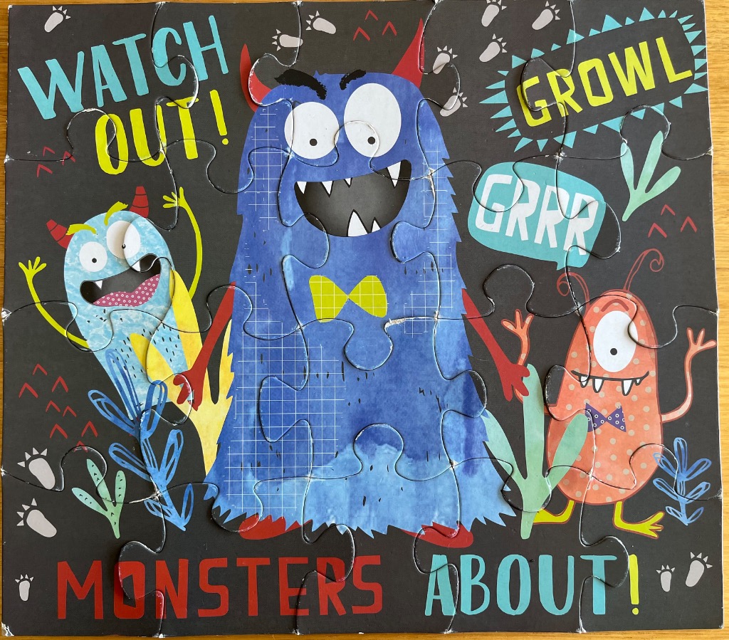 A cartoon illustration of three colorful monsters on a black background with playful text.