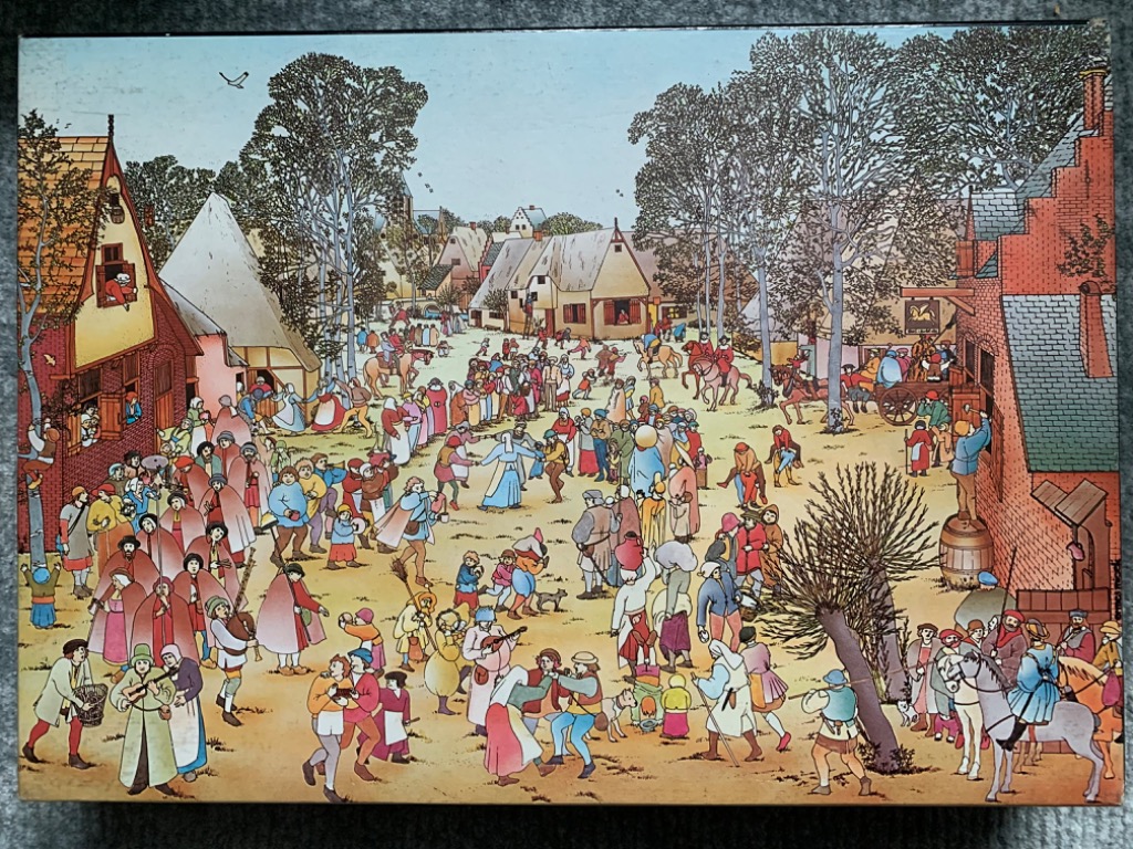 A lively, densely populated medieval village scene with many people dancing and gathering in a town square.