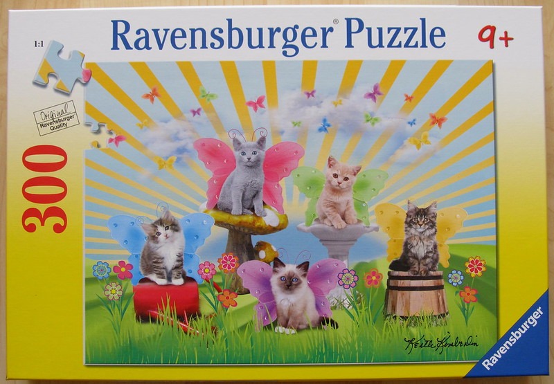 A whimsical illustration of four kittens with colorful butterfly wings sitting in a garden scene.