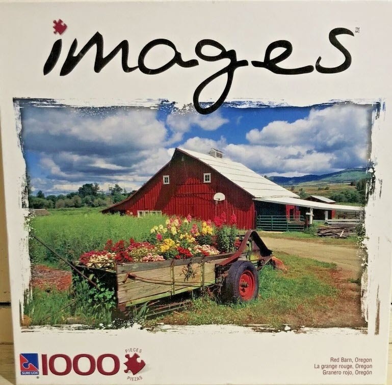 A red barn in a rural landscape with a wooden wagon filled with colorful flowers in the foreground.