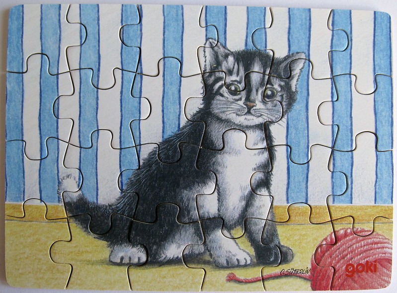An illustration of a small black and white kitten sitting on a yellow floor against a blue-striped wall.