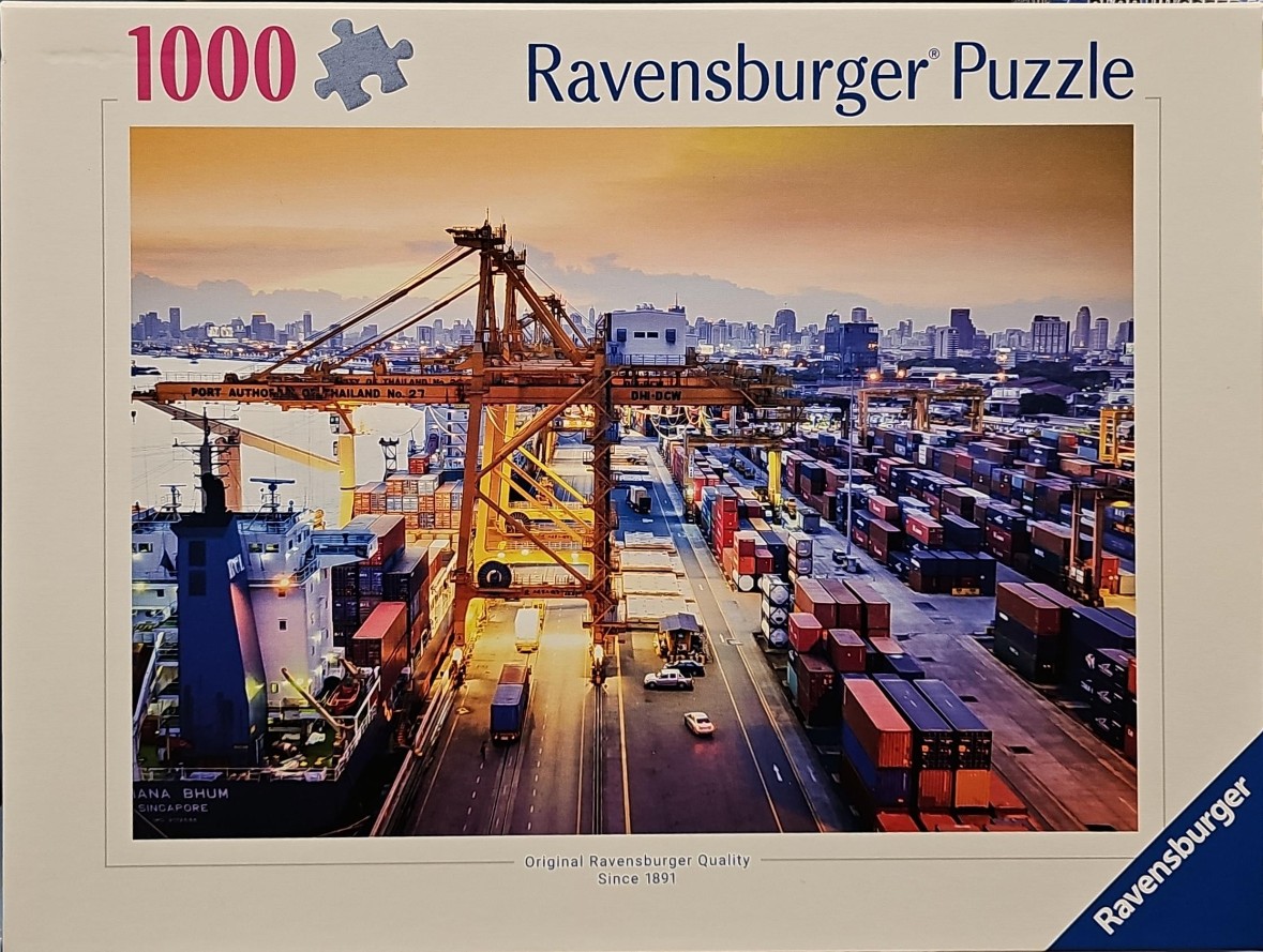 A panoramic view of a busy shipping port at sunset with large orange cranes and container stacks.