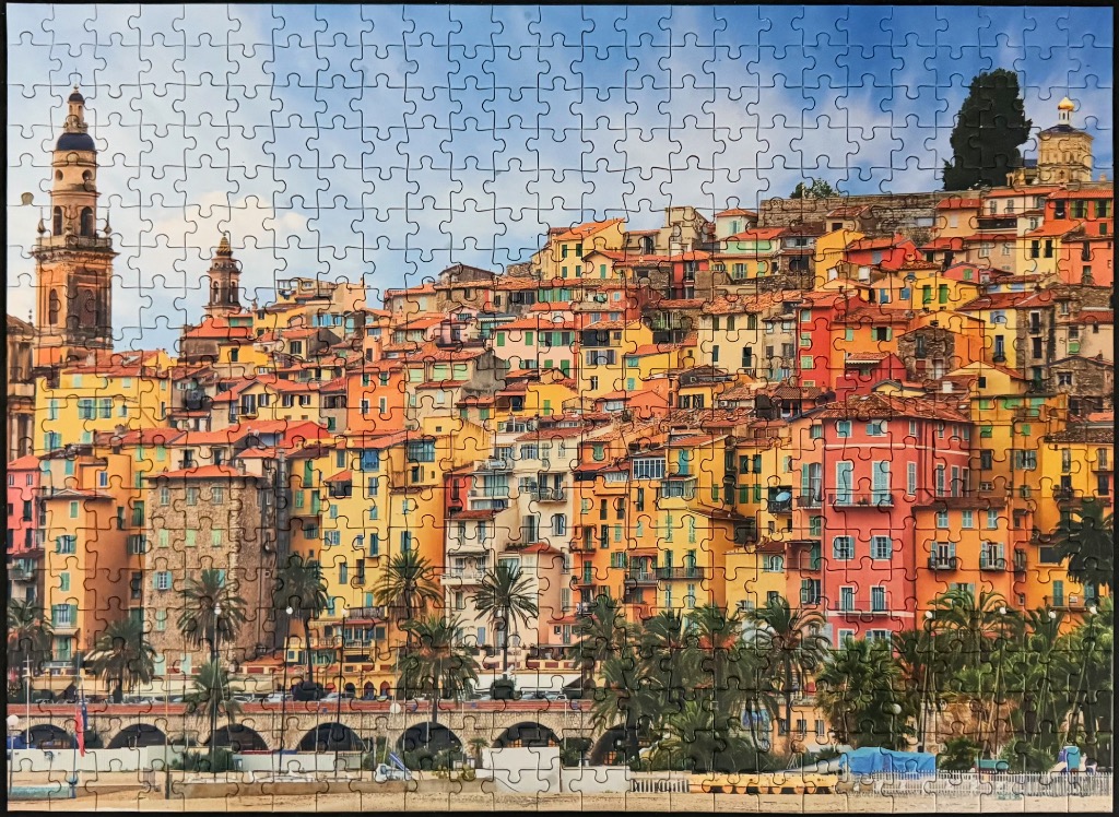 A panoramic view of the colorful hilltop town of Menton, France, against a clear blue sky.