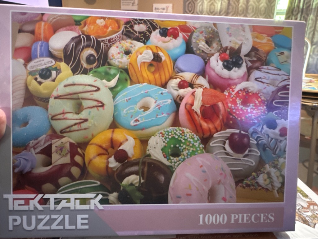 A close-up photograph of an assortment of colorful glazed donuts and pastries packed tightly together.