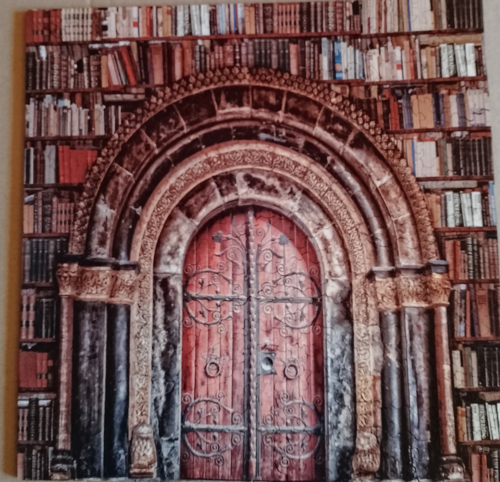 Ornate red doors with intricate metalwork, framed by a stone archway and overflowing bookshelves.