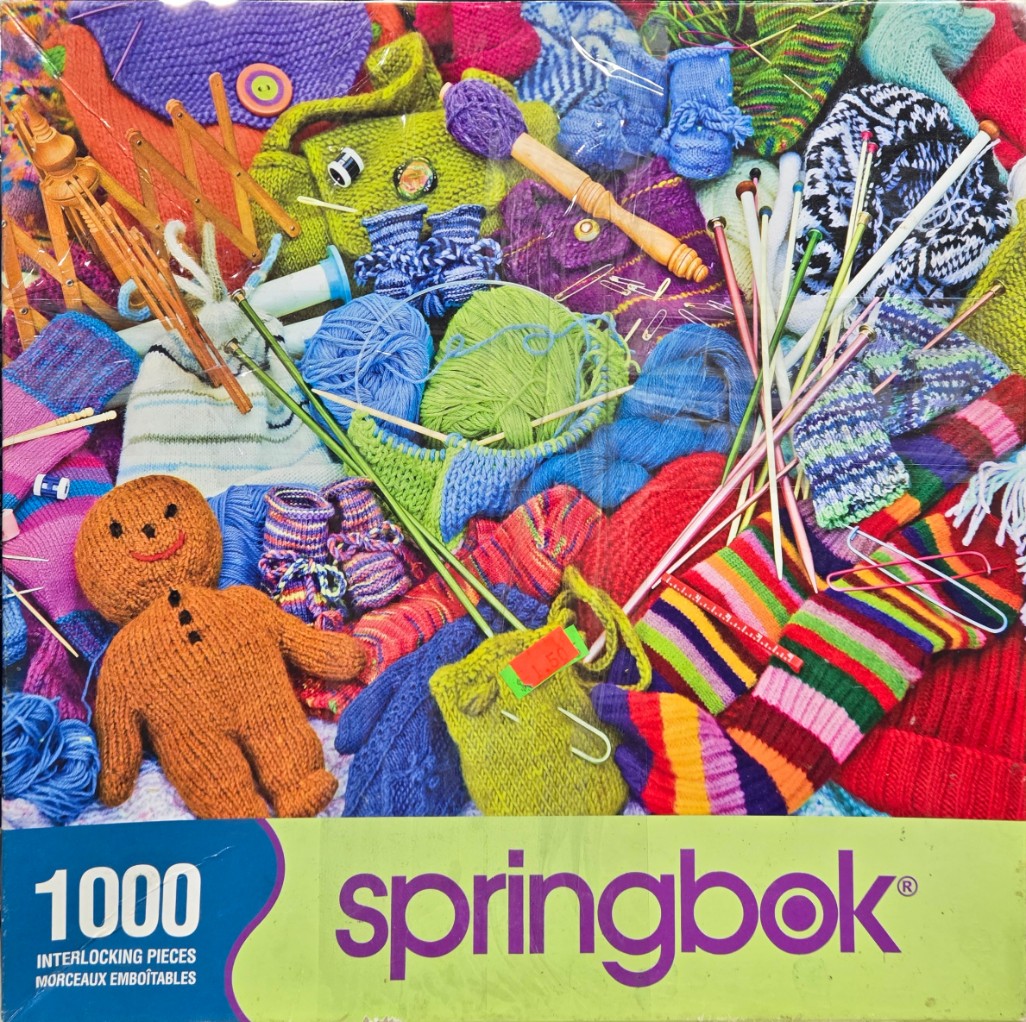 A chaotic, colorful flat-lay of assorted knitted items, yarn skeins, and knitting needles.