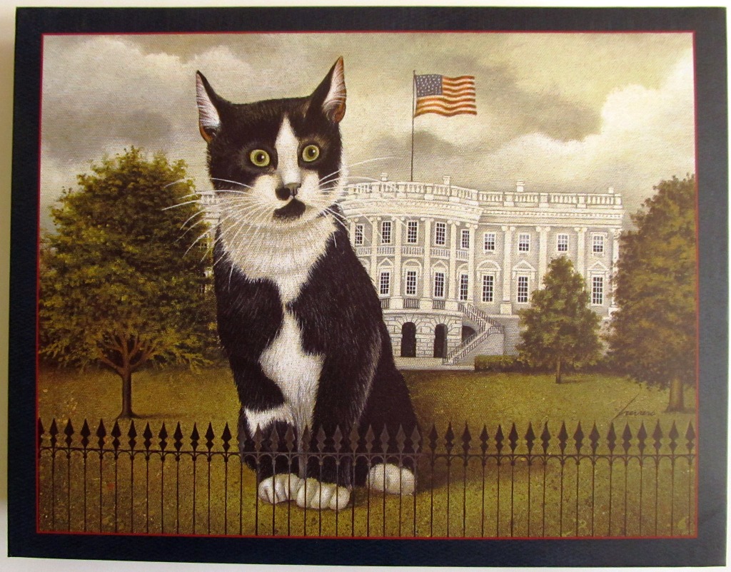 A black and white tuxedo cat sitting in front of a painting of the White House.
