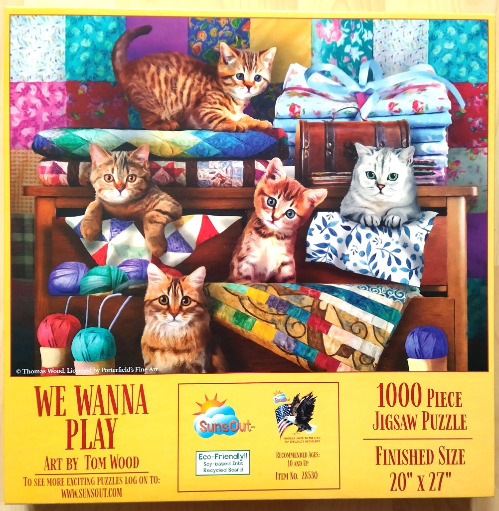 Five kittens exploring a wooden shelf filled with quilts and balls of yarn.
