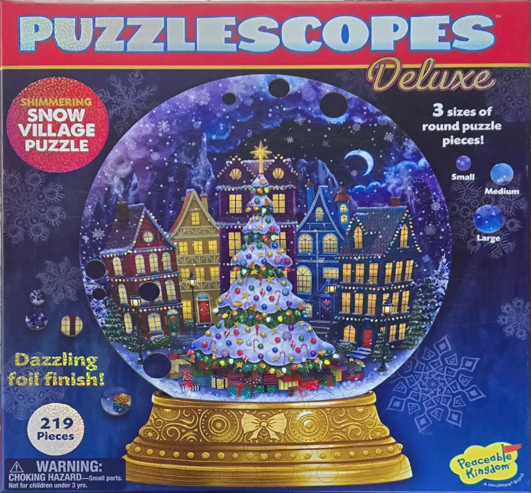 A decorative snow globe featuring a festive Christmas village scene with a large, glowing tree at the center.