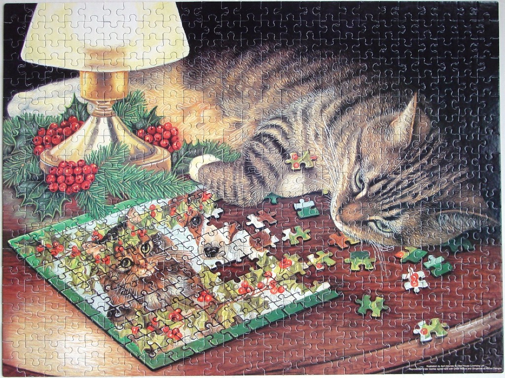 A tabby cat resting on a wooden table next to a Christmas-themed illustration