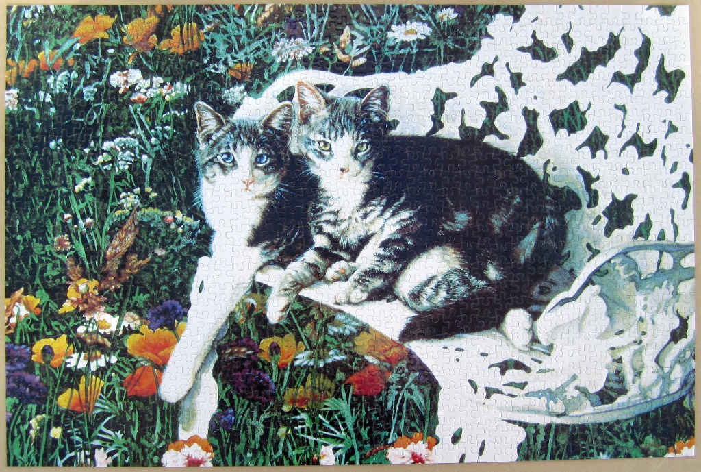 Two tabby cats resting on an ornate white garden bench amidst a field of colorful wildflowers.