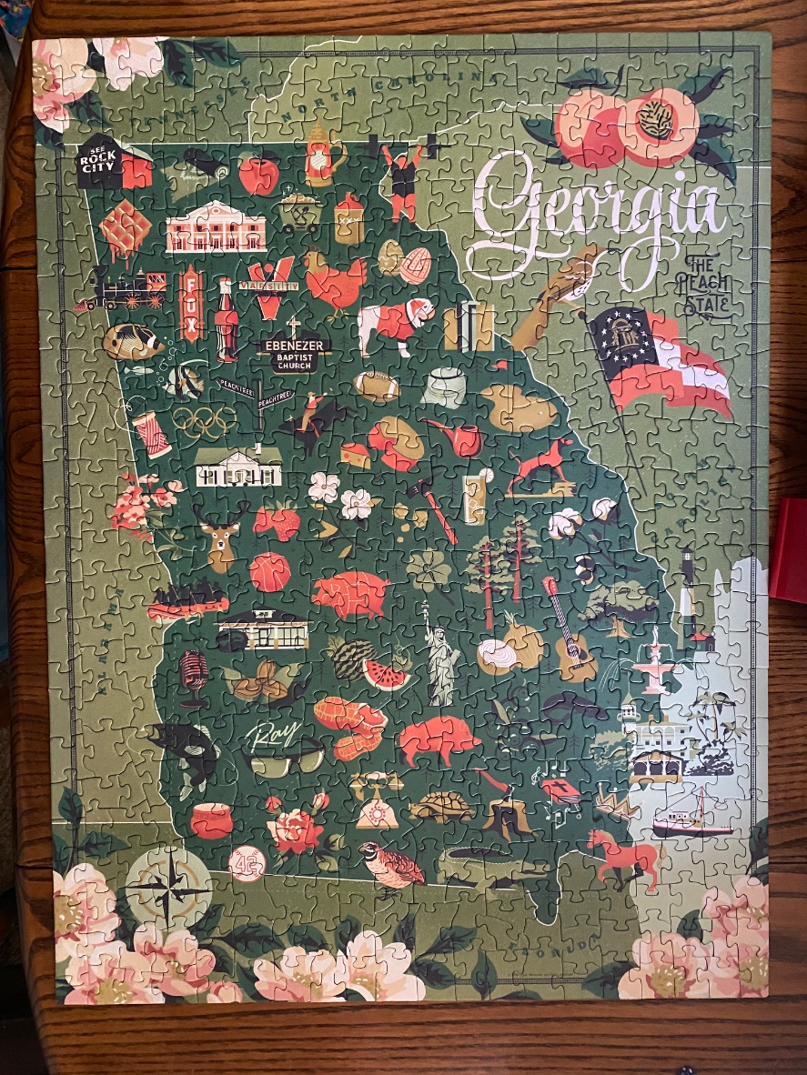 An illustrated map of Georgia featuring cultural icons and landmarks in a muted olive green palette.