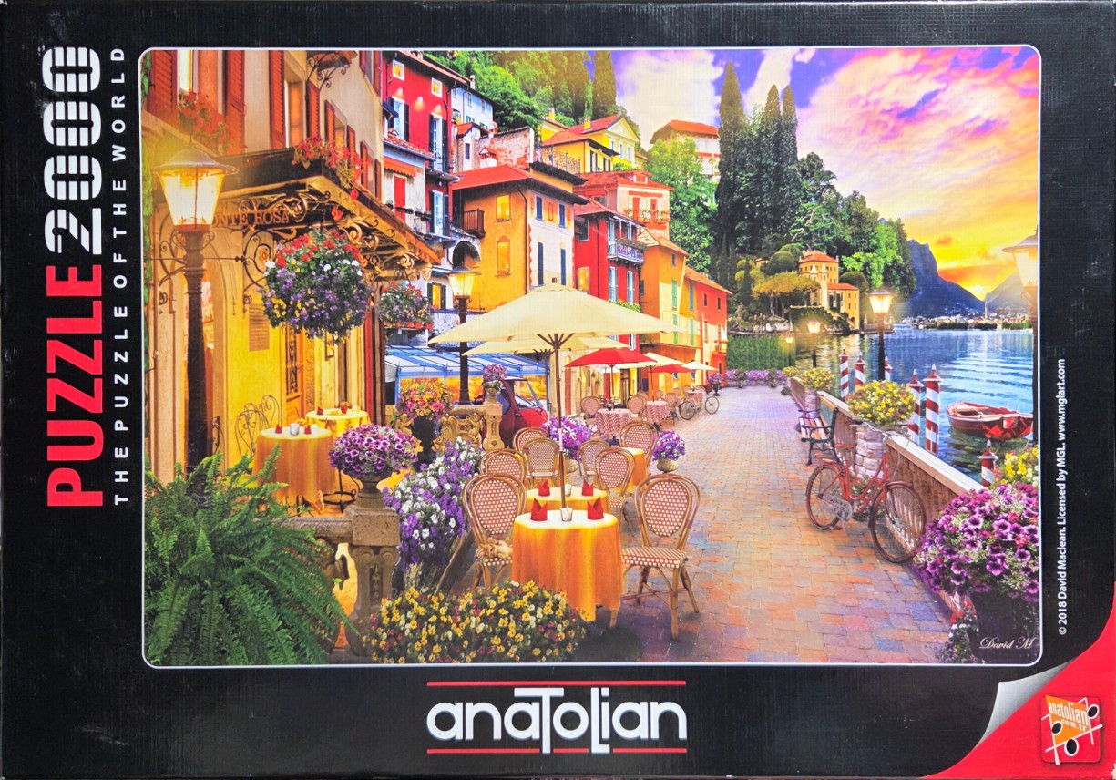 An outdoor restaurant patio beside a Mediterranean lake at sunset.