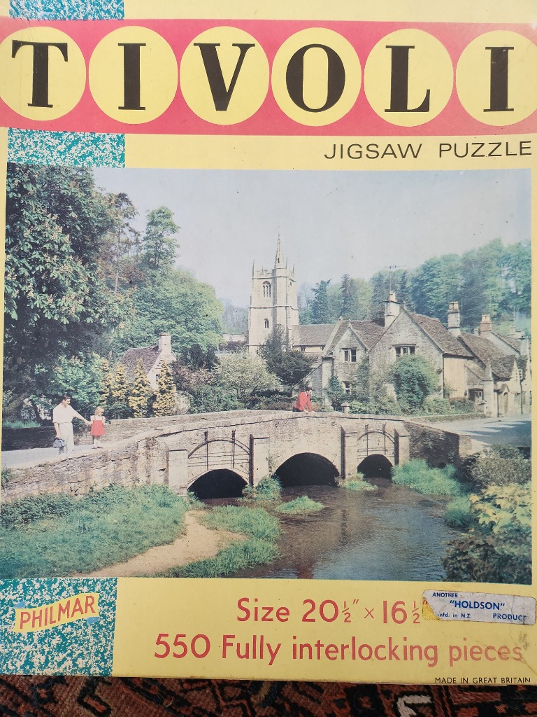 A peaceful English countryside scene with a stone bridge, stream, and old church, captured in a vintage photograph.