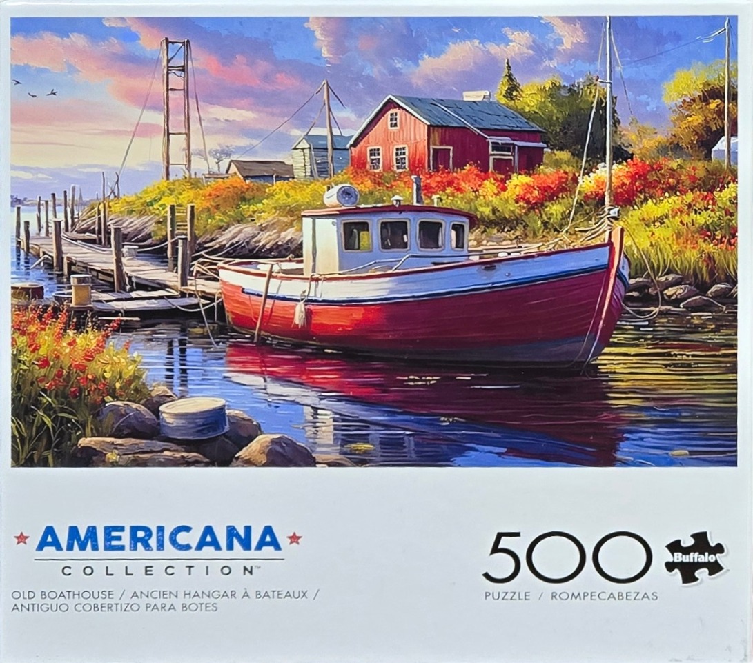 A red fishing boat moored by a wooden dock near a red barn at sunset