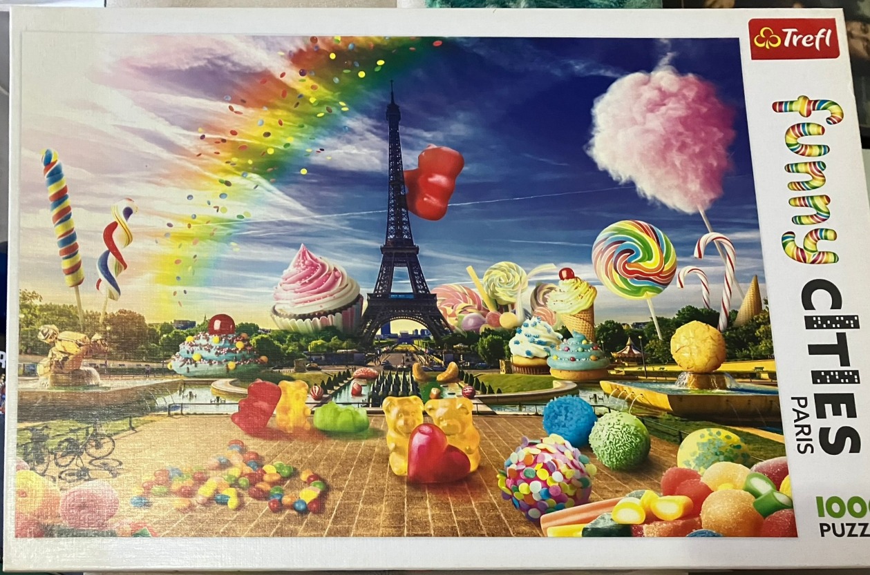A whimsical surrealist montage of the Eiffel Tower surrounded by giant sweets and candies under a vibrant rainbow.