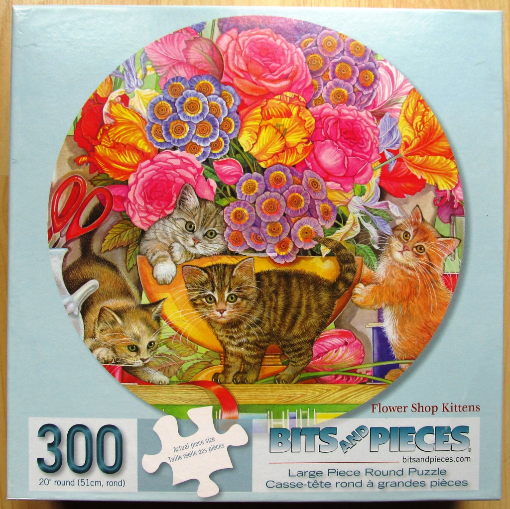 Three kittens playing among a vibrant bouquet of flowers in a round composition.