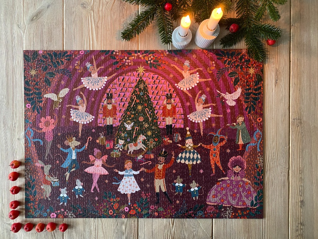 A whimsical Nutcracker-themed illustration in shades of pink, red, and dark plum, featuring ballet dancers and toy soldiers.