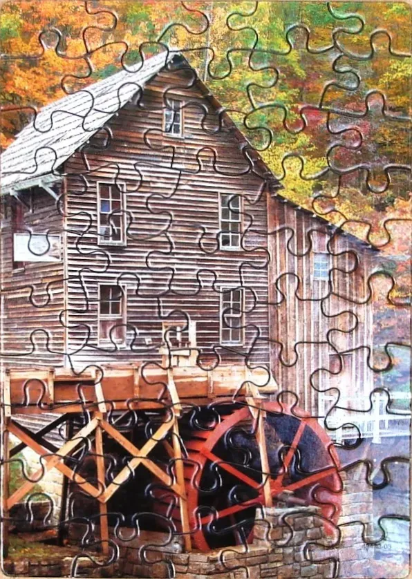 A rustic wooden water mill sits against a backdrop of vibrant autumn foliage.