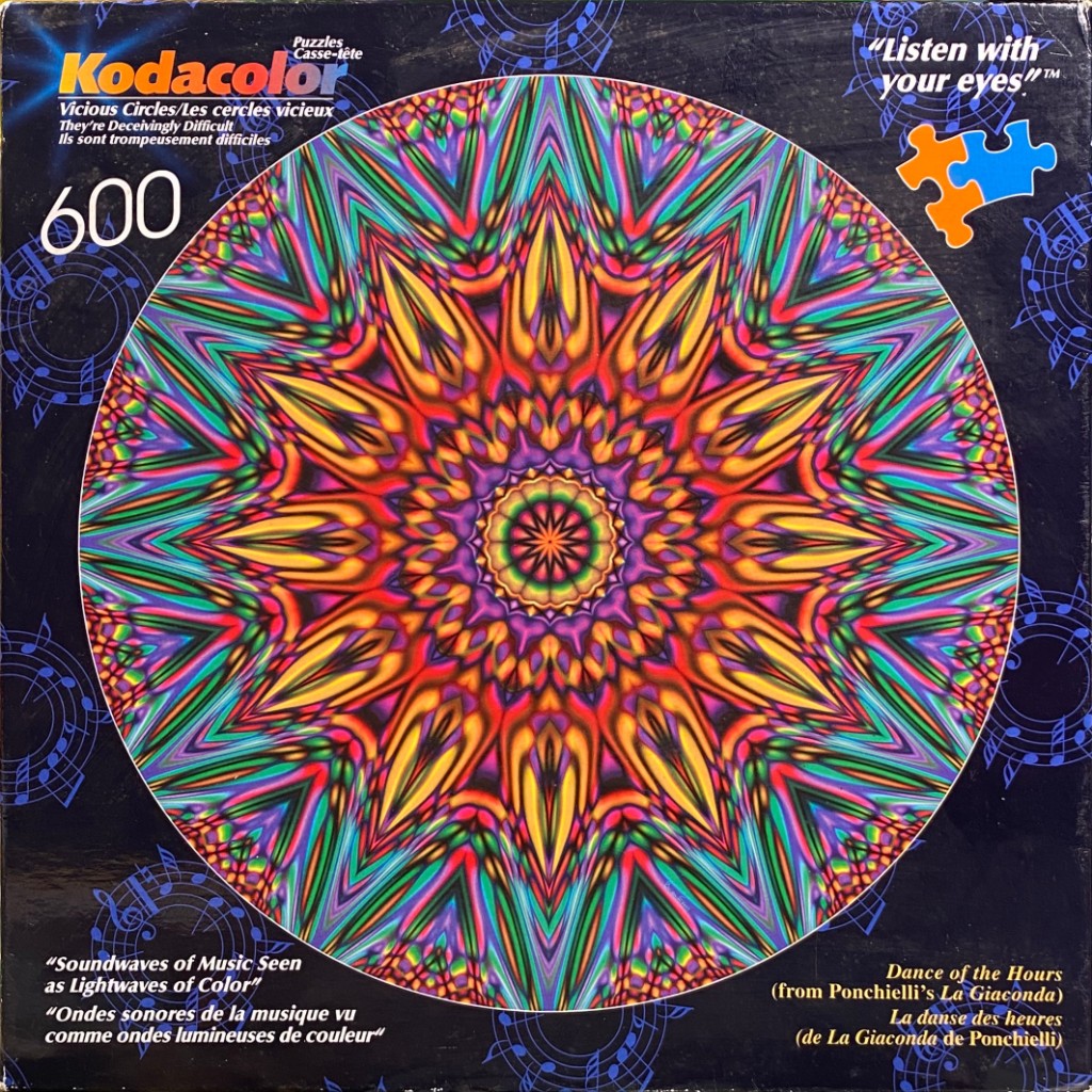 A vibrant, kaleidoscopic circular mandala design featuring radially symmetrical, multi-colored patterns.