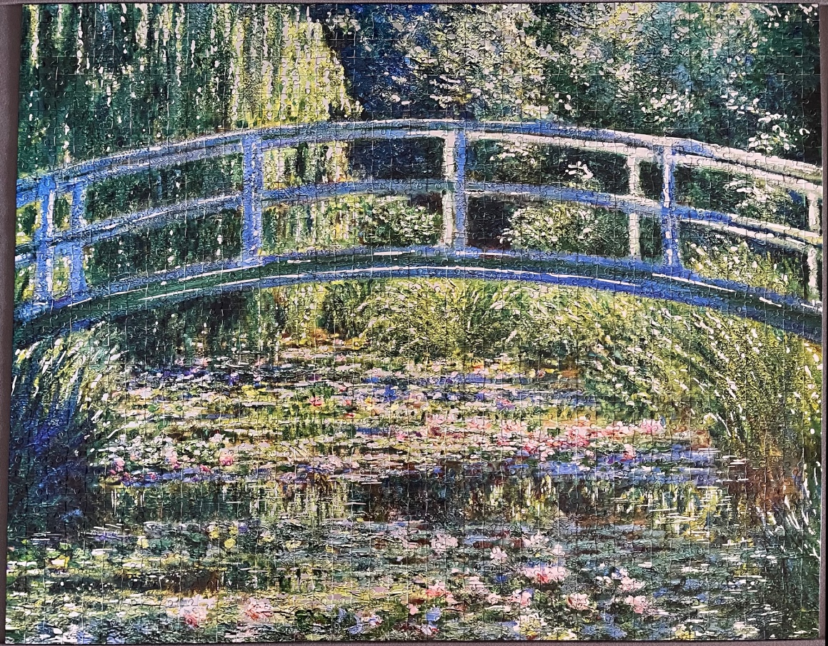Impressionist painting of a blue wooden bridge arched over a pond filled with water lilies and lush greenery.