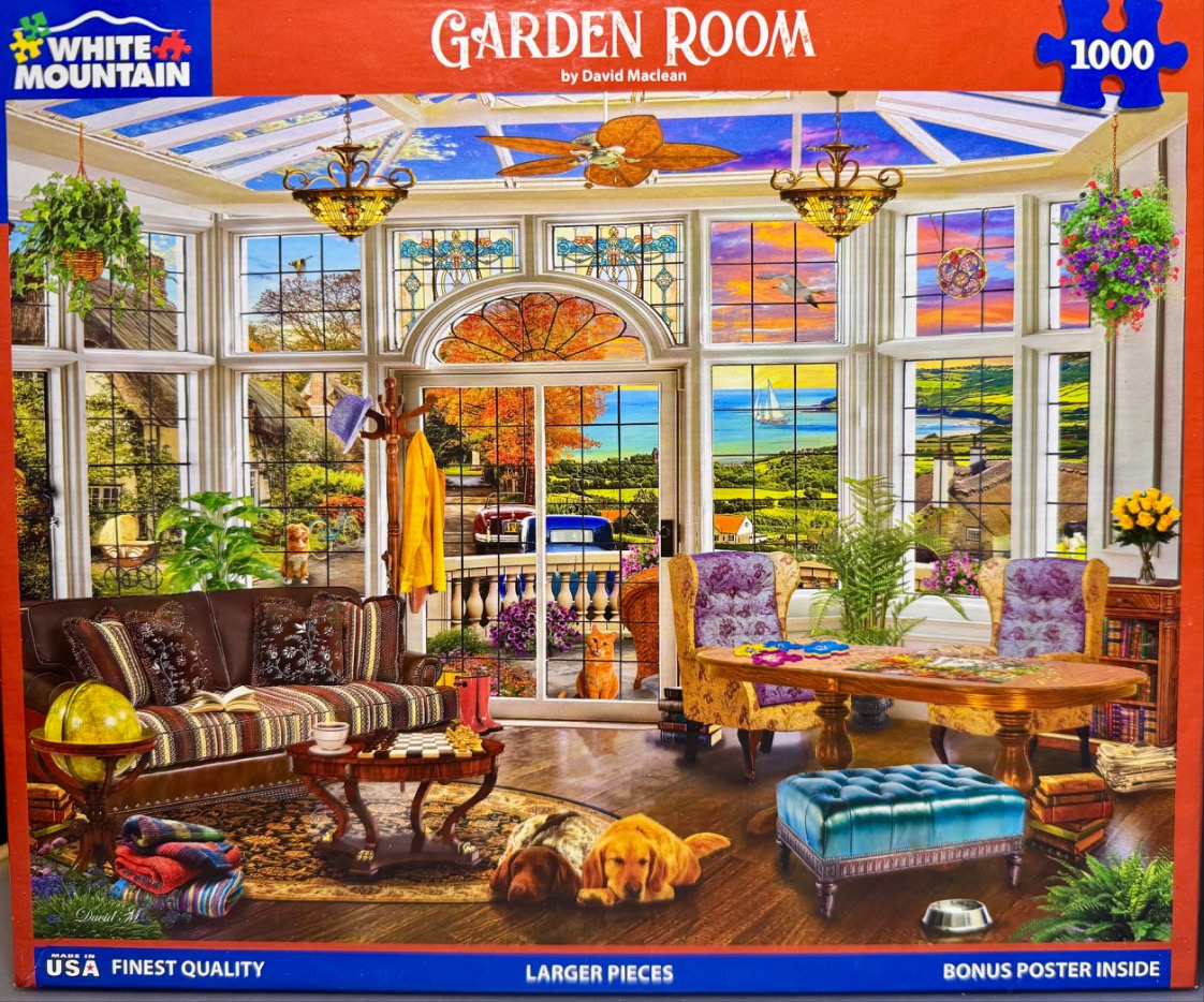 A cozy, sunlit garden room with large windows overlooking a scenic coastal view.