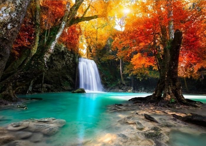 A cascading waterfall emptying into a turquoise pool surrounded by vibrant autumn trees.