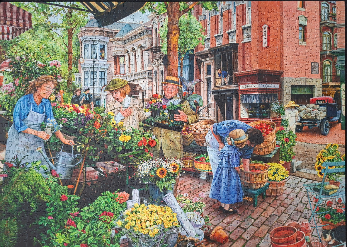 A bustling outdoor flower market on a brick street in front of historic brick buildings.