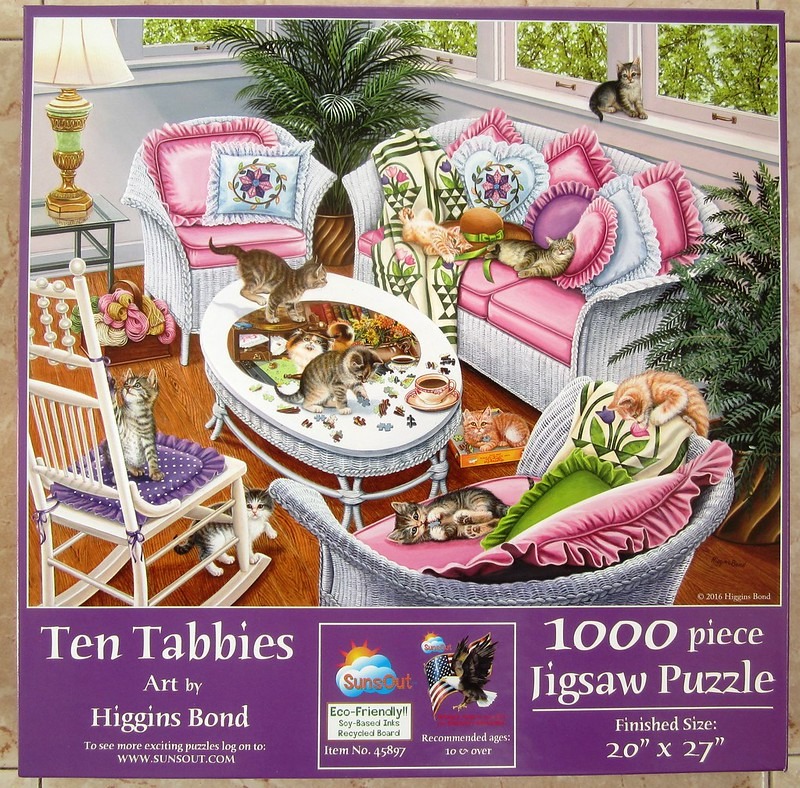 A cozy sunroom interior featuring ten tabby kittens playing on white wicker furniture and a coffee table.