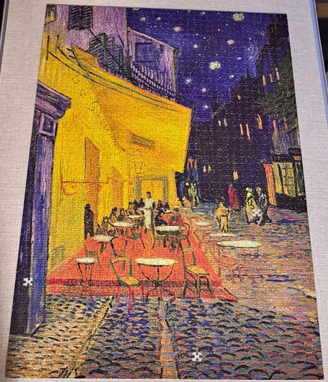 A reproduction of Van Gogh's Cafe Terrace at Night with a vibrant yellow cafe set against a deep blue starry sky.