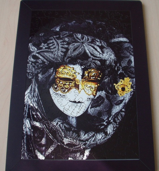 A close-up of a Venetian masquerade mask decorated in intricate black lace and brilliant gold filigree.